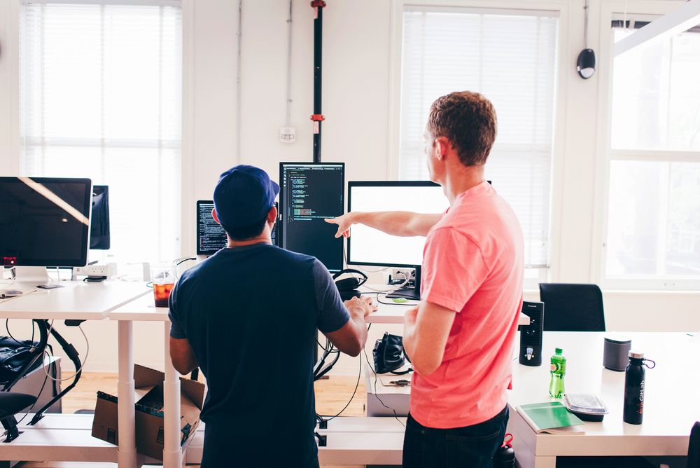 two people pointing at a computer screen in an office