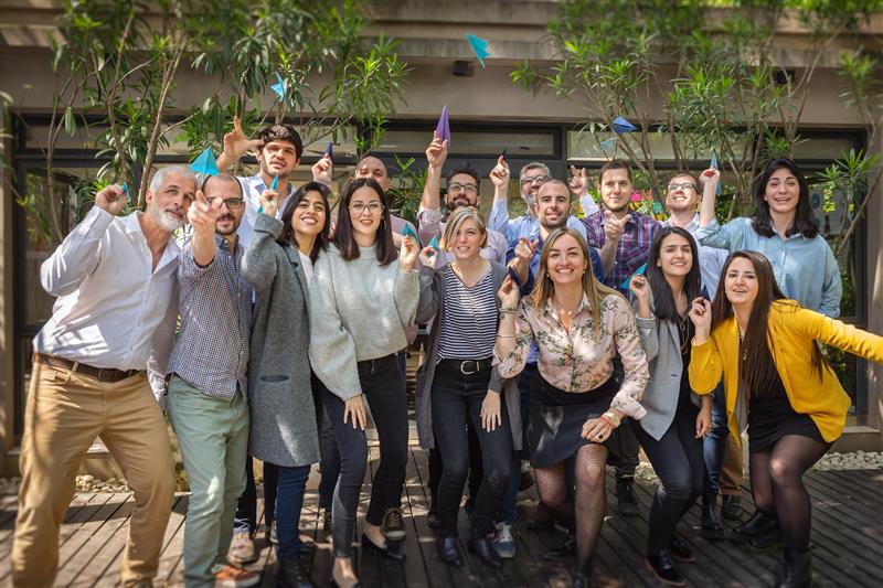 group photo of people outside throwing paper planes