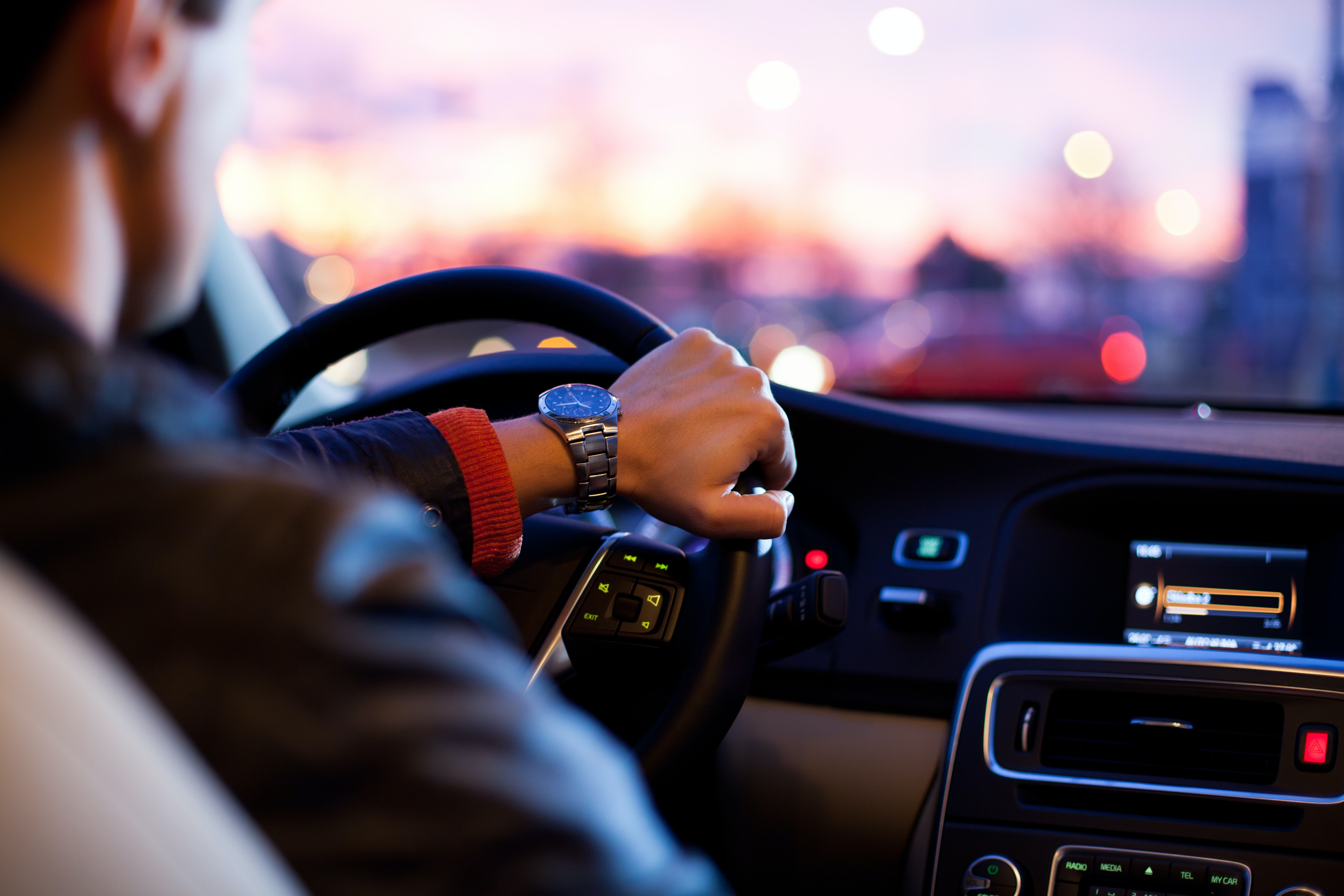 A person with their hand on their steering wheel