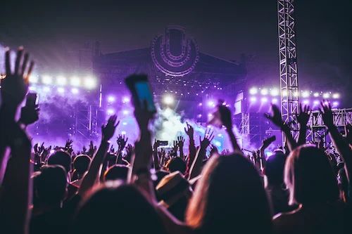 A big crowd of people with their hands up at a concert