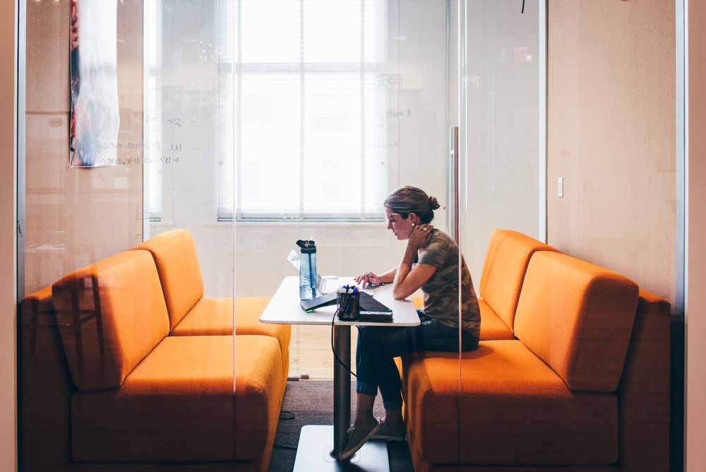 a person sitting alone with a computer in and office booth