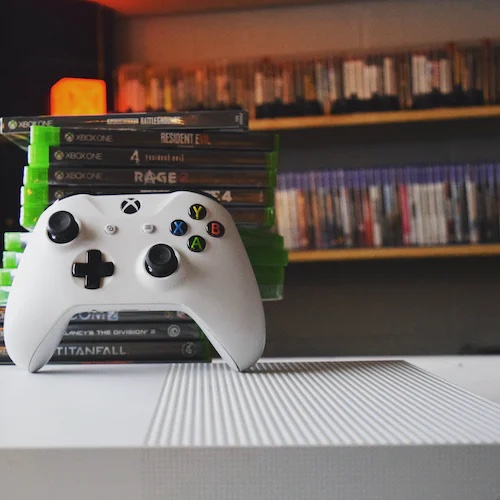 White game controller in front of shelves of games